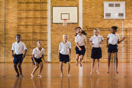 运动制服学生在体育馆跳跃的学生群体童年运动男生游戏知识小学生班级体育木头教育背景