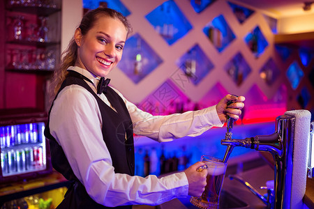 酒吧工作素材快乐的酒吧女招待在玻璃杯中倒啤酒的肖像背景