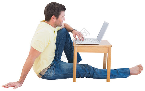 使用笔记本电脑微笑的人休闲服装地面桌子男性男人技术背景图片