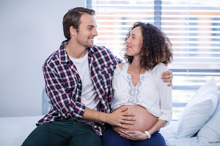 在病房中抚慰孕妇的男子孕产拥抱快乐孕妇装医疗医务室互动怀孕腹部保健背景图片
