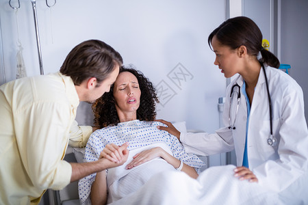 医生和男人在病房中抚慰孕妇卫生互动感情医院孕产孕妇装混血服务劳动男性背景图片