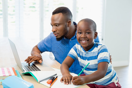 教育性的父亲使用笔记本电脑 儿子在客厅做功课亲密感互联网教育家庭生活闲暇男生孩子休闲房子沟通背景