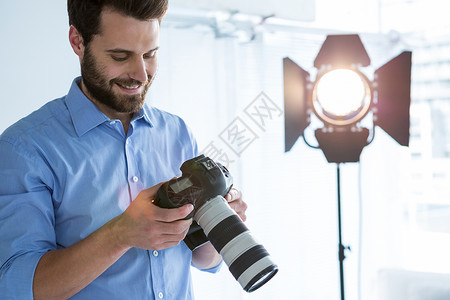 菲涅耳男性摄影师翻阅数码相机中拍摄照片的男摄影师摄影工作生活闲暇服装魅力工作室聚光灯相机现实背景