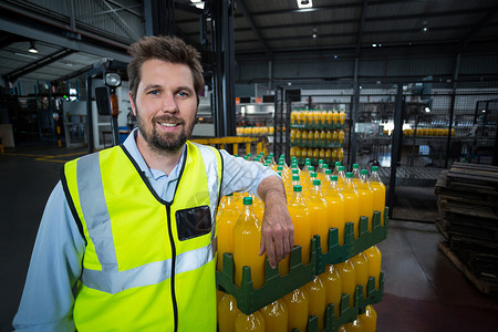行数依赖包装的橙汁瓶子箱的工厂工人的肖像背景