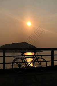 旧式自行车 栅栏 海洋 山丘 太阳晒太阳假期土地生活人行道阴影日落旅行橙子公园背景图片