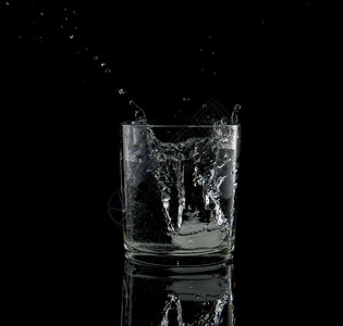 液体反映从水杯中落下的冰块上喷出背景