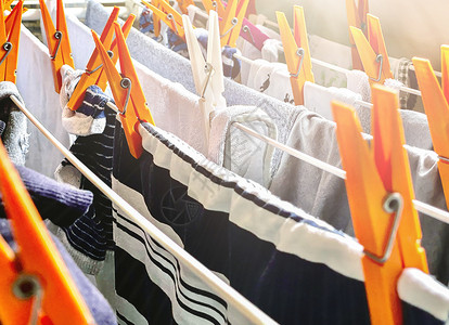 衣服没有素材一组橙色衣夹在晾衣架上晾干衣物 衣服挂在房子里晾干 家务和卫生衣绳洗衣店家庭团体别针烘干机纺织品塑料橙子毛巾背景