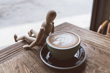 卡人模型人热辣咖啡或茶杯中的卡普奇诺 由木匠靠在绿色的杯子上身体男人人体男性数字邮政木偶模型姿势咖啡背景