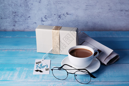 蓝色小喇叭标签父亲节快乐 一杯咖啡 带礼物盒和眼镜礼物手工玻璃胡子报纸展示男人木头家庭知识背景