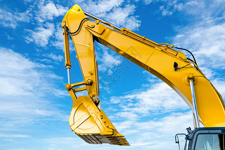 反铲挖掘机黄色背面有液压活塞臂 与蓝色天空相对背景