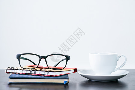 桌上咖啡杯和眼镜职场咖啡杯子笔记本桌子早餐饮料桌面办公室空间背景图片