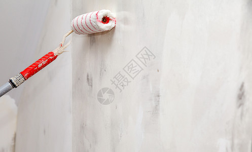 带胶水滚压闭板的工人油漆墙壁背景