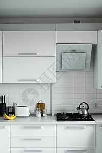 舒适的白色厨房 外墙漆成白色 现代厨房干净的室内设计 炉灶 烤面包机和厨房油烟机 厨房用品背景图片