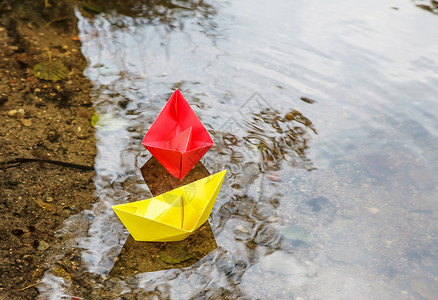 小纸船两艘多色纸船漂浮在溪流上池塘舰队折叠公园自由季节女性乐趣玩具团体背景