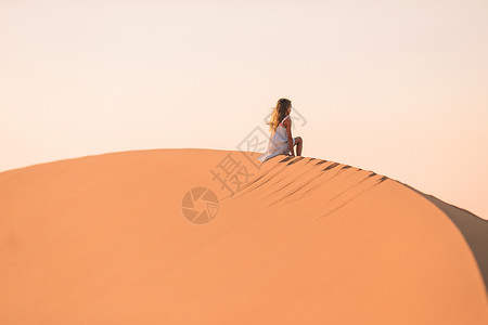 在阿拉伯联合酋长国沙漠中的沙丘中女童居于沙丘中裙子滚动山脊干旱风景栖息地天空环境荒野乐趣背景