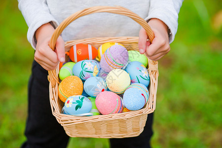 复活节篮子关紧的篮子 充满了儿童手中的丰富多彩的复活节鸡蛋季节花园女孩草地庆典活动打猎喜悦乐趣孩子背景