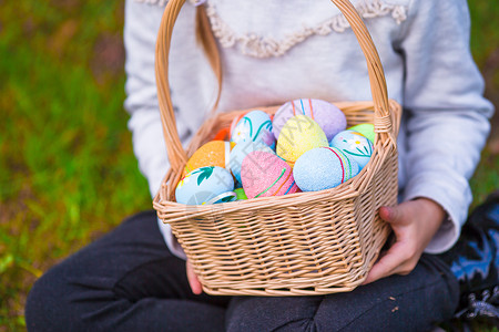 草绘关紧的篮子 充满了儿童手中的丰富多彩的复活节鸡蛋喜悦节日孩子乐趣草地假期传统植物活动花园背景