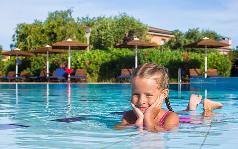 在游泳池看摄影机时 坐在游泳池里可爱的小女孩休息幸福假期乐趣喜悦微笑相机快乐女孩闲暇背景图片