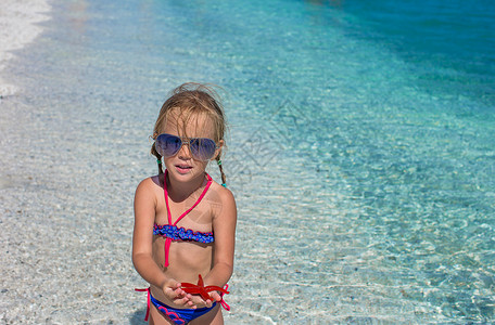送水女孩儿热带海滩上有海星的小可爱女孩儿动物群身体星星假期旅游孩子生活热情尖刺手指背景