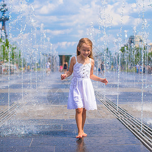 热天在户外喷泉玩得开心的可爱女孩友谊街道时间乐趣反射孩子城市公园喜悦童年背景