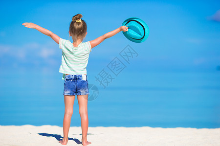 加勒比蓝色在海滩度假时戴着帽子的 笑着微笑的可爱快乐小女孩海岸喜悦假期海景童年支撑闲暇海岸线蓝色太阳镜背景