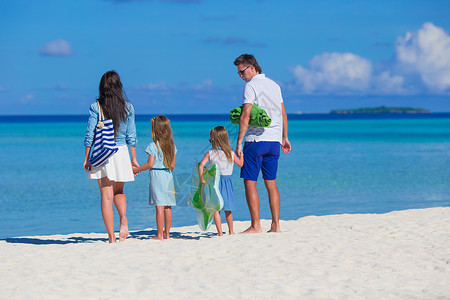 海滩家庭四岁四岁的年轻家庭在沙滩度假女儿海滨孩子们父母女性阳光孩子父亲享受姐姐背景