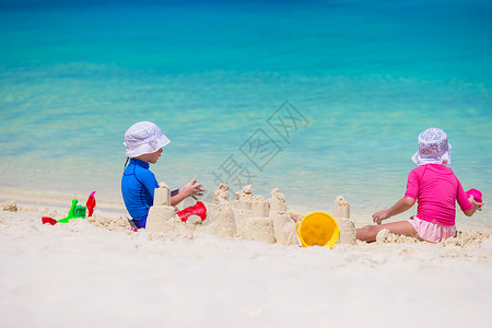 可爱沙堡热带假期玩沙滩玩具的可爱小女孩沙堡享受青年床垫女孩情调海滨闲暇家庭女儿背景