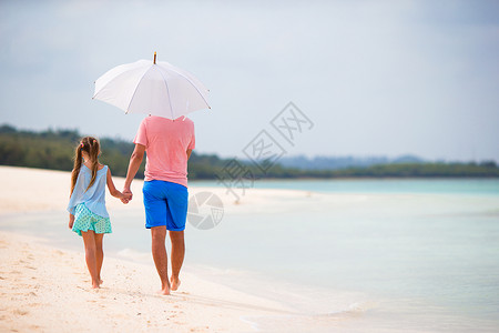 雨伞为孩子遮风挡雨的父亲带雨伞的海滩上家庭背影孩子蓝色海洋阳伞海岸女孩海岸线异国爸爸父母背景
