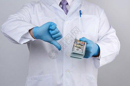 医院账单穿蓝色制服和乳胶手套的医生 一只手留着很多医院从业者货币工资腐败金融手术外科受贿薪水背景