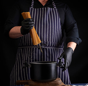 专业国外炖锅穿黑色乳胶手套的厨师 带条纹围裙持有生长西瓜背景