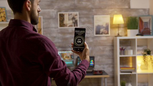 男人用智能灯光应用来打开客厅的灯光监控灯泡智能灯命令房子互联网控制创新手机电话背景图片