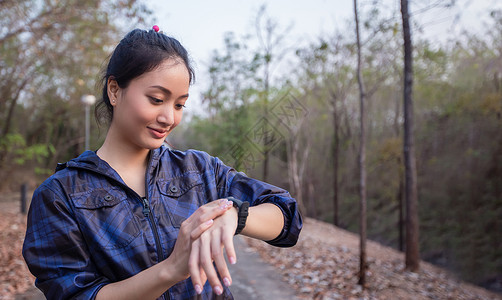 亚洲女性正在急促启动运动表或智能手表以进行慢跑背景图片