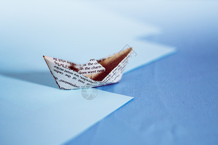 旧报纸造的纸船蓝色设计航程资产自由运输保险旅行工艺金融背景图片