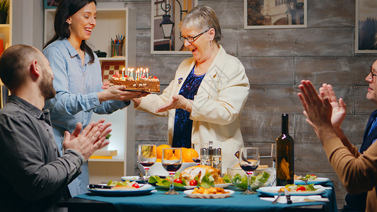 与家人一起庆祝生日的年长妇女父亲团体父母女士蜡烛祖母亲戚们母亲房子祖父背景图片