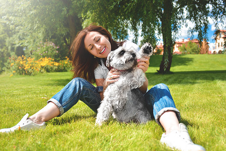 在阳光明媚的日子里 漂亮的成年白人快乐女人和她心爱的狗在公园里休息 女性躺在草地上 微笑着看着镜头 爱动物概念说谎朋友女孩房子卷图片