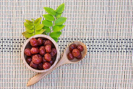 糖浆中的鹅莓放在木碗和竹棍上的勺子里高清图片