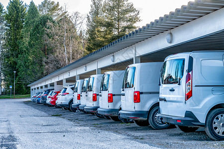 在停车场的一排白色汽车和货车上特写照片 屋顶保护免受阳光和雨雪的影响 针对不同天气条件的安全斯堪的纳维亚运输业务背景图片