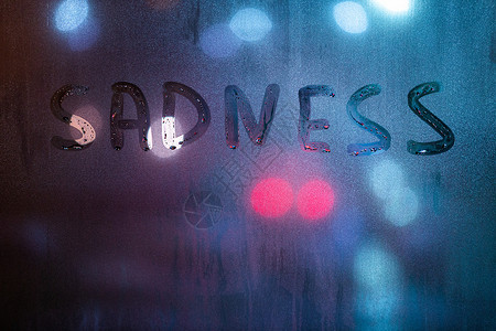 标题心理素材用手指在深夜湿玻璃上写着悲伤的字 背景有模糊的蓝色和红色灯光背景