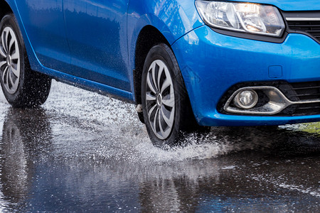 蓝色车横穿水坑 在日光闭合时泼水 有选择性地聚焦交通飞溅城市下雨气候汽车灾难车辆沥青天气背景图片
