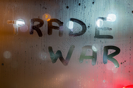 夜间湿窗玻璃上写的贸易战字样 背景模糊背景图片