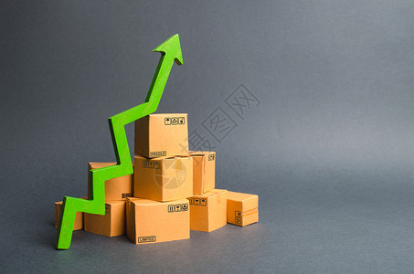 一堆纸板箱和一个绿色的向上箭头 商品和产品生产的增长率 经济指标不断增加 增加消费者需求 增加出口或进口背景