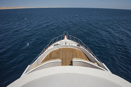 在一艘大型游艇的船首上观光奢华海景蓝色旅行地平线热带栏杆海洋假期航行背景