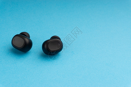 耳机耳塞设计蓝色背景上的无线耳塞或耳机旅行黑色音乐扬声器蓝牙娱乐口袋宏观工作室耳朵背景