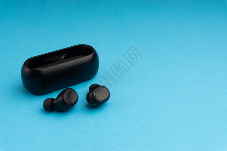 耳机耳塞设计蓝色背景上的无线耳塞或耳机黑色蓝牙工具波浪耳朵收音机助听器立体声充电音乐背景