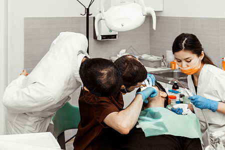 牙科技师精致两个牙医治疗一个病人 牙医的专业制服和设备 医疗保健装备医生工作场所 牙科治愈牙齿工具牙科技师女士衰变医学外科卫生矫正背景