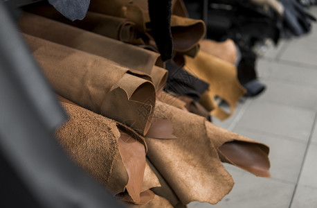 不同的皮革卷 彩色皮革碎片 天然棕红色皮革卷 制造箱包 鞋子 服装和配饰的原材料阴影身体制造业工艺生产皮肤作坊鹿皮工厂手工背景图片