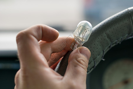 人手的手指握着车内损坏的灯泡专题损害车辆缺陷车轮玻璃男人汽车车把指标背景图片