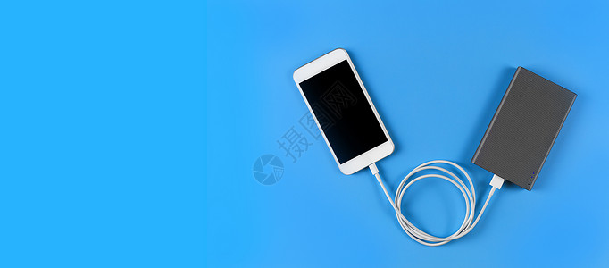 充电电话蓝色背景上带移动电源的顶视图智能手机充电电缆线充电器连接器充值充电宝横幅商业适配器电池细胞背景