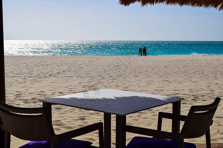 浪漫的 Bucuti  Tara 度假村位于阿鲁巴岛东侧的鹰海滩 棕榈树 白色沙滩伞 几朵云和美丽的白色沙滩令人叹为观止支撑闲暇背景