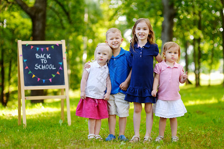 四个兴奋的小孩 在黑板旁边粉笔女孩喜悦小学生幼儿园姐妹旗帜写作同学兄弟背景图片